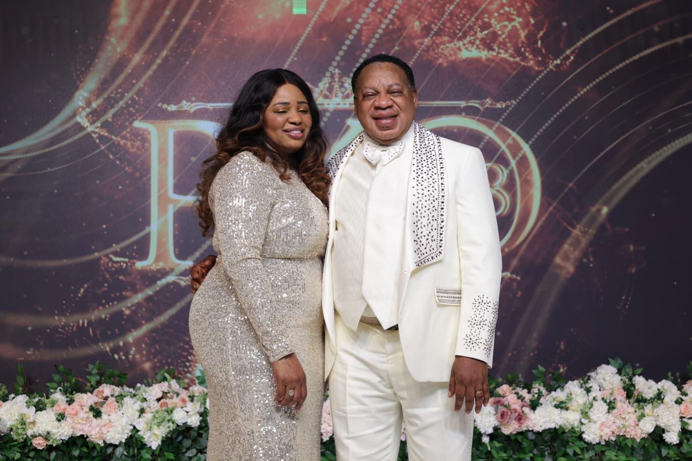 Reverend Ken in white celebration attire beside a loved one